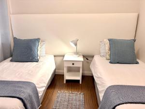 2 aparte bedden in een kamer met een nachtkastje bij 105 Gouriqua Mosselbay in Mosselbaai