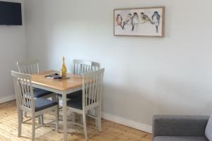 a dining room table with chairs and a picture of birds on the wall at Apartment - Sleeps 2 - Wood Fire - Parking in Cullyhanna