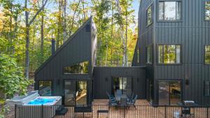 a black house with a swimming pool and trees at 70s Retro Escape Hot Tub, Sauna & Arcade Games in Gaylord