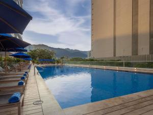 a large swimming pool with chairs and umbrellas next to a building at Mercure Santa Marta Emile in Santa Marta