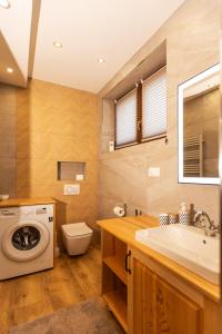 a bathroom with a washing machine and a sink at Apartament Pod Magurą in Witów