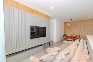 a living room with a couch and a tv on a wall at Praia Brava - Central entre Itajaí e BC - 2 Qts e Ar in Itajaí