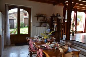 comedor con mesa, sillas y puerta en Chambre d'hôtes La Framboisine, en Bourgvilain