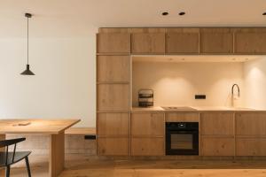a kitchen with wooden cabinets and a table at Apartment Garden Loggia in Novacella