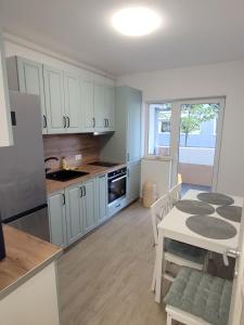 a kitchen with white cabinets and a table and a dining room at Hunyadi Luxury Kogalniceanu in Sibiu