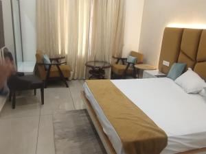 a hotel room with a bed and some chairs at hitkari palace in Hāpur