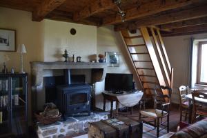 a living room with a fireplace and a table and a chair at Gîte la Framboisine in Bourgvilain