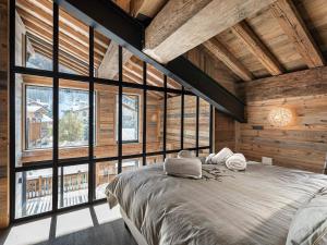 a bedroom with a large bed in a room with windows at Chalet d'Exception avec Piscine, Hammam et Ascenseur à Val d'Isère, Proche des Pistes - FR-1-567-38 in Val dʼIsère +9 photos