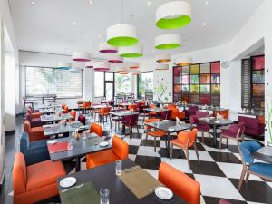 a restaurant with tables and chairs and windows at Ibis Styles Accra Airport in Accra