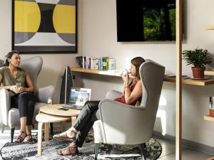 zwei Frauen sitzen auf einem Stuhl in einem Büro in der Unterkunft Aparthotel Adagio access Colombes La Défense in Colombes