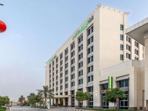 a large white building on a city street at Ibis Styles Dragon Mart Dubai in Dubai