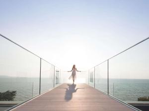 a woman walking on a walkway over the ocean at Veranda Resort Pattaya - MGallery Collection, Accor Hotel in Jomtien Beach