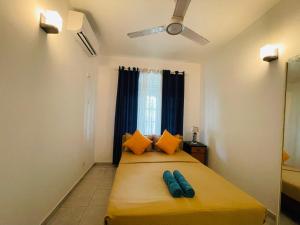 a bedroom with a bed with orange pillows and a ceiling fan at White N Villa in Wadduwa