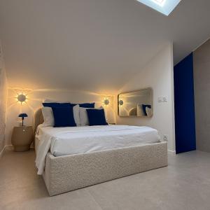 une chambre blanche avec un grand lit avec des oreillers bleus dans l'établissement La Plage maison de plage à Port Leucate, à Port-Leucate