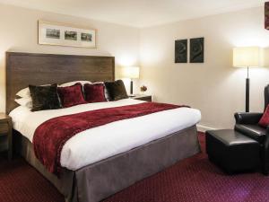 a hotel room with a large bed and a chair at Mercure Haydock Hotel in Haydock