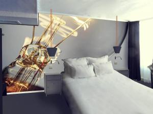Un dormitorio con una cama y un cuadro en la pared. en Mercure Paris Malakoff Parc des Expositions, en Malakoff