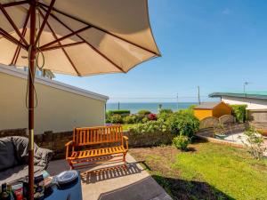 eine Terrasse mit einer Bank und einem Sonnenschirm in der Unterkunft 4 Bed in Ogmore-By-Sea 87141 in Saint Brides Major