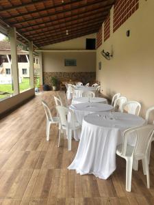 una stanza con tavoli bianchi e sedie bianche di Sítio dos Guedes a Guapimirim