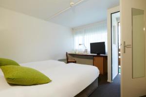 Un dormitorio con una cama y un escritorio con televisión. en Campanile Lille - Lomme, en Lomme 18 fotos más