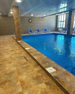 een groot zwembad met blauwe stoelen in een gebouw bij Alvina Complex Apartment in Tsachkadzor