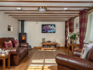 a living room with brown leather furniture and a tv at 1 Bed in Bwlch BN270 in Llansantffread