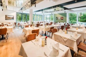 a restaurant with white tables and chairs and windows at Überwasser Hotel in Cuxhaven