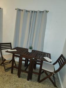 a wooden table and two chairs with a potted plant on it at First Floor 2 Bed Apartment in La Ceiba