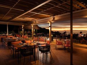 a restaurant with tables and chairs with a sunset in the background at Avista Hideaway Phuket Patong - MGallery in Patong Beach