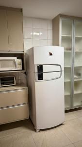 frigorifero bianco in cucina con forno a microonde di Apartamento moderno a 2 quadras da Praia da Costa - completo, espaçoso e com mimo especial a Vila Velha