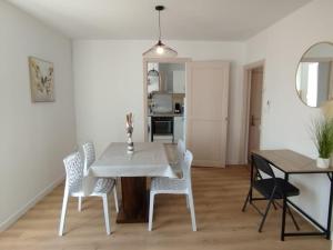 a dining room with a white table and chairs at Appart 2 Chambres, Proche Gare, Wifi, Jardin, Parking in Montélimar