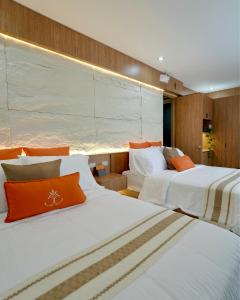 two beds in a large room with orange pillows at La Manna Events and Leisure Place 