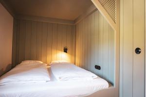 a bed with white sheets and a light on it at STUBN in der Frasdorfer Hütte in Frasdorf