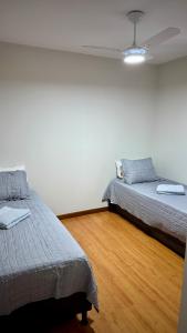 due letti in una stanza con pavimenti in legno di Apartamento moderno a 2 quadras da Praia da Costa - completo, espaçoso e com mimo especial a Vila Velha