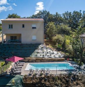 une maison avec une piscine, des chaises et un parasol dans l'établissement Gite Les Bouches Rouges, à Vesseaux
