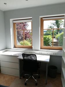 a desk with a chair in a room with two windows at Himmelthal Apartment in Eschau