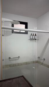 un bagno con box doccia in vetro e 2 bottiglie di Apartamento moderno a 2 quadras da Praia da Costa - completo, espaçoso e com mimo especial a Vila Velha