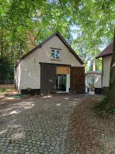 a building with a garage and a tree at De Steeg in Kalmthout