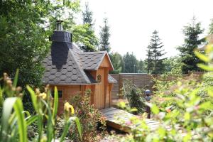 a small house with a black roof in a garden at Gästehaus am schmalen See UG haftungsbeschränkt in Lauchhammer