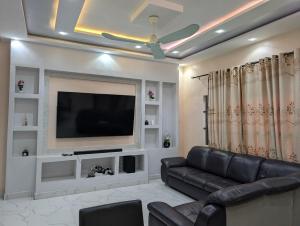 a living room with a black leather couch and a flat screen tv at Porto-Novo Charme Townhouse in Porto-Novo