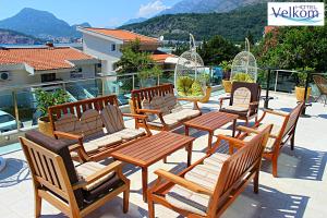 a group of wooden chairs and tables on a balcony at Hotel Velkom in Sutomore