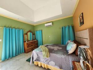 a bedroom with blue curtains and a bed and a dresser at Louise's Hideaway in Black River