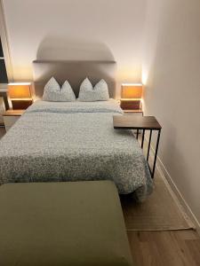 Un dormitorio con una cama y una mesita de noche con dos lámparas. en Newly Renovated Stylish & Spacious Studio, en Huttwil