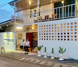 two people sitting on the porch of a building at บ้านปู่ทอง Grandpa's House in Chiang Khan +3 photos
