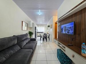 Una sala de estar con un sofá y un televisor de pantalla plana. en 2 quartos, casa em bairro tranquilo 5 minutos do centro, en Foz do Iguaçu