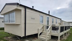 a large white tiny house with a porch at South Breeze Caravans in Camber