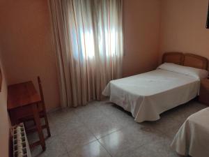a small bedroom with two beds and a window at Hotel Peñarroya in Argamasilla de Alba