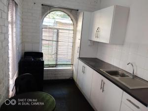 a small kitchen with a sink and a window at Titas Cozy cottage in Johannesburg