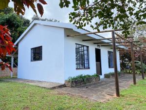 a white house with black windows at Luxury modern farm cottage with sea view in Southbroom