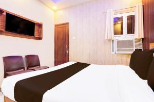 a bedroom with a bed and two chairs and a television at Hotel O Blue Stone Near Singapore Mall Lucknow in Gomti Nagar