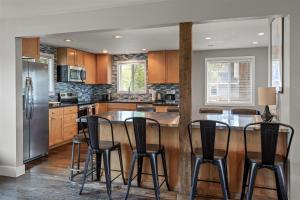 a kitchen with a bar with black stools at Bluebird Day - Brooks House in Deschutes River Woods